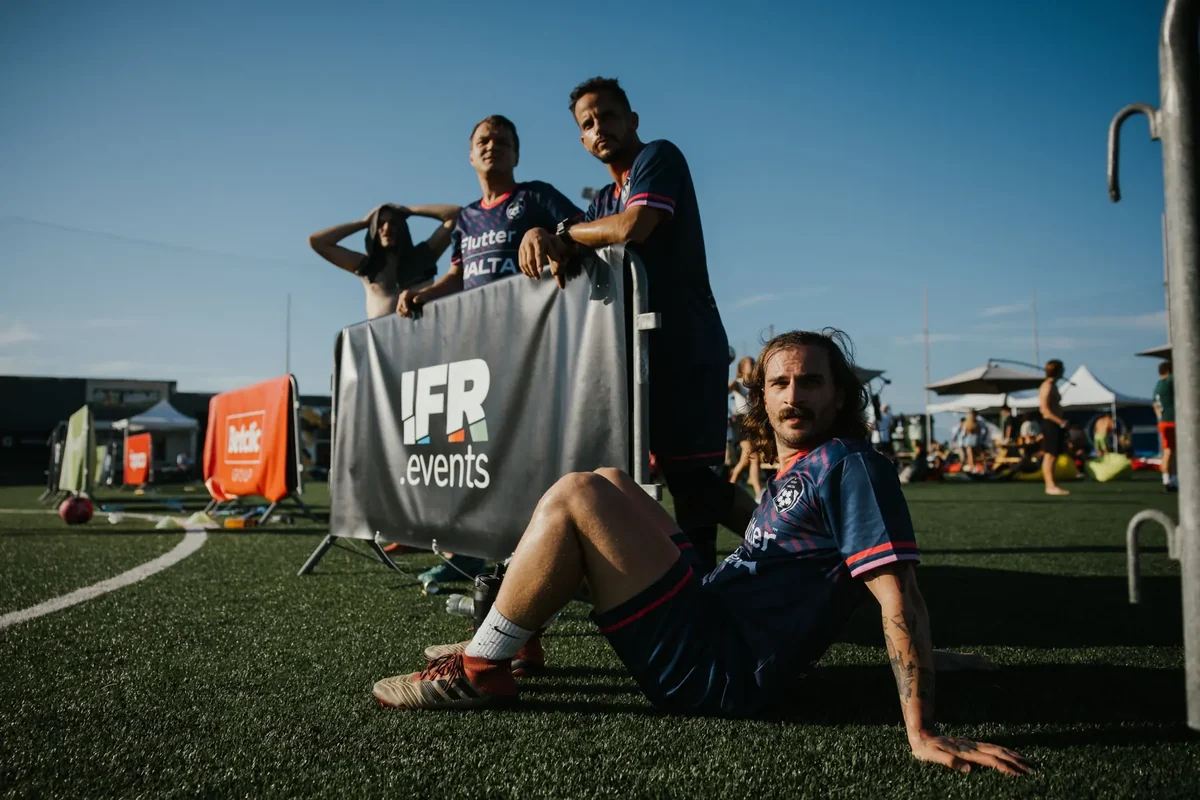 Flutter Malta colleagues together beside the pitch at an IFR event