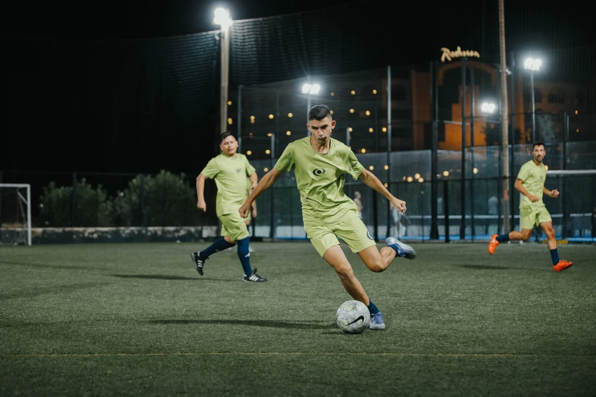 A male player strikes the ball under floodlights with teammates running behind him at a previous IFR football event