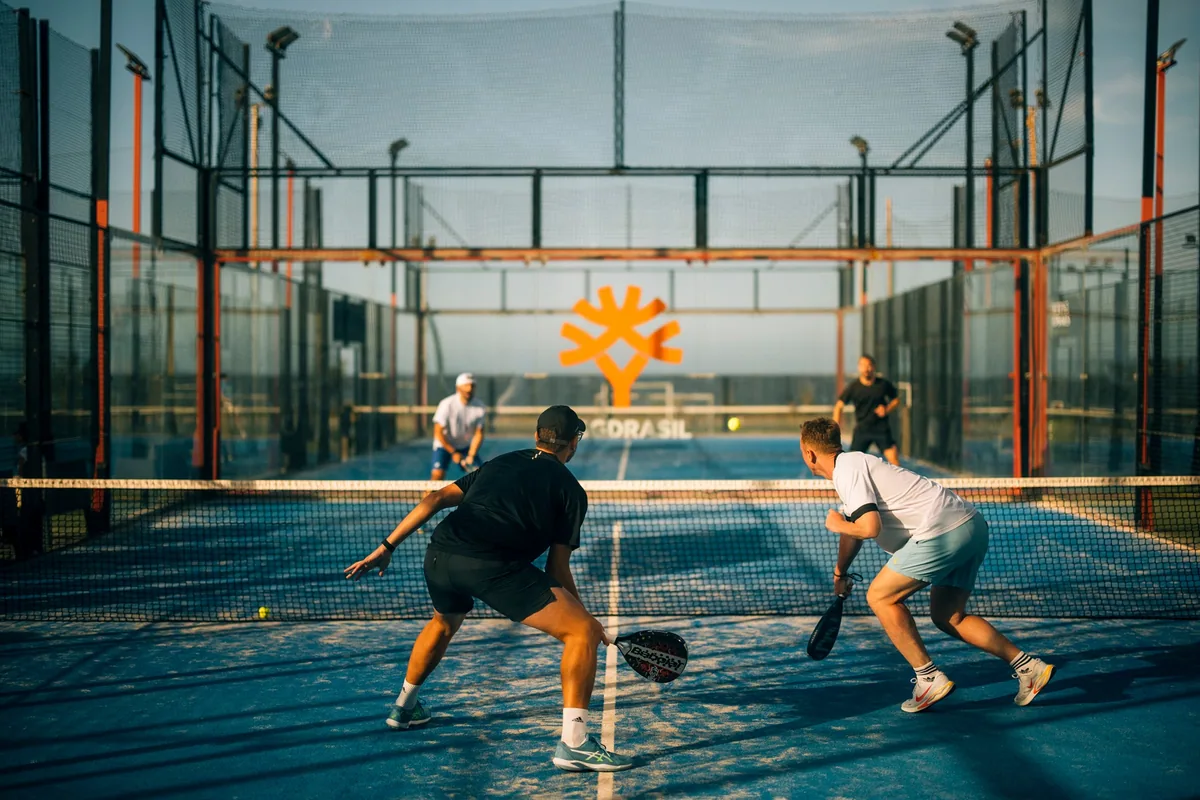 Two players rally on a sunlit court at the IFR Padel Cup